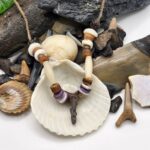 Shark carved from fossil shark tooth on a necklace with shell, wood, and bone beads.