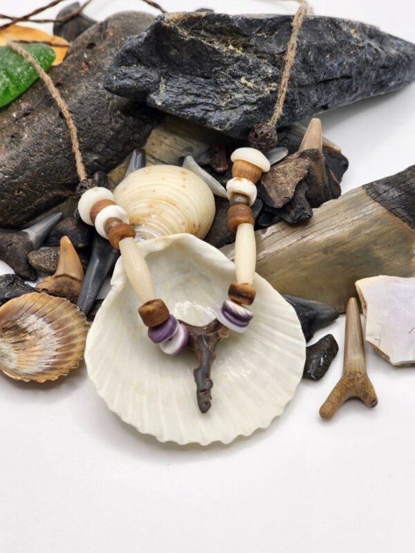 Shark carved from fossil shark tooth on a necklace with shell, wood, and bone beads.