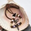 Shark carved from fossil shark tooth on a necklace with shell, wood, and bone beads.