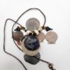 A shark carved into a coconut disc and painted gray as a pendant on a necklace with fossilized shark teeth, puka shells, and coconut beads